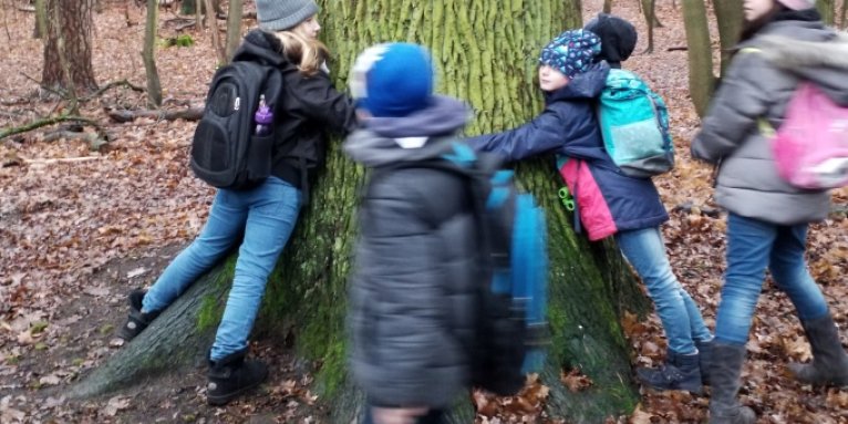 Kindergruppe umarmt einen Baum - Foto: Christine Kuhnert