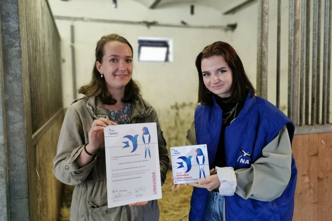 Carolin Eichhorst (li.) und NABU-Mitarbeiterin Charleen Matthwes (re.) bei der Übergabe der Auszeichnung im Pferdestall der Familie – Foto: Janna Einöder